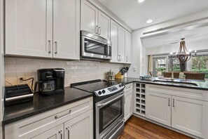 A modern kitchen with white cabinetry, a built-in microwave, a gas stove, and a coffee maker.