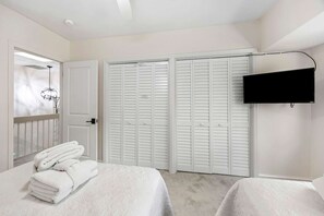 A hotel room with a bed, a TV, a closet, and a door.