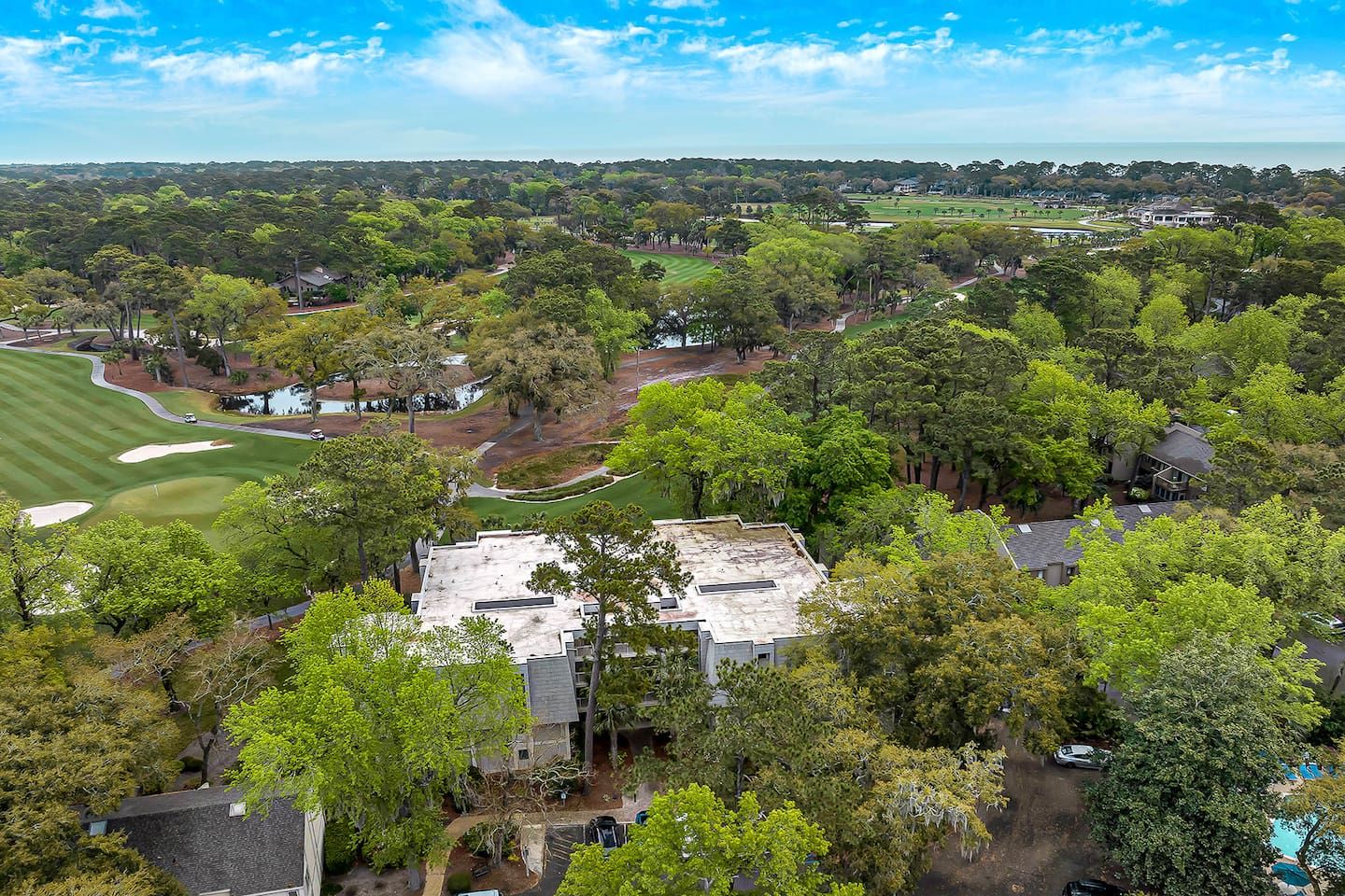 A golf course with a clubhouse and residential buildings surrounded by trees.