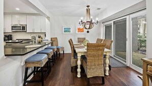 A modern kitchen with a central island, dining chairs, and a chandelier. - Spacious 3BR Villa | Plantation Club, Sea Pines (Hilton Head Island)
