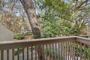 A wooden deck with a railing overlooking a landscaped garden with various trees and shrubs.