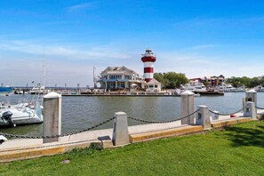 A marina with a lighthouse, boats, and a building with a blue roof.