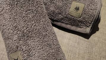 Ein grauer, gefalteter Teppich mit einem Etikett, das ihn als Produkt des Greenwich Polo Club kennzeichnet.