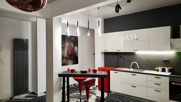 A modern kitchen with white cabinets, a red chair, and a black and white patterned floor. - fruit tower  (THESSALONIKI)