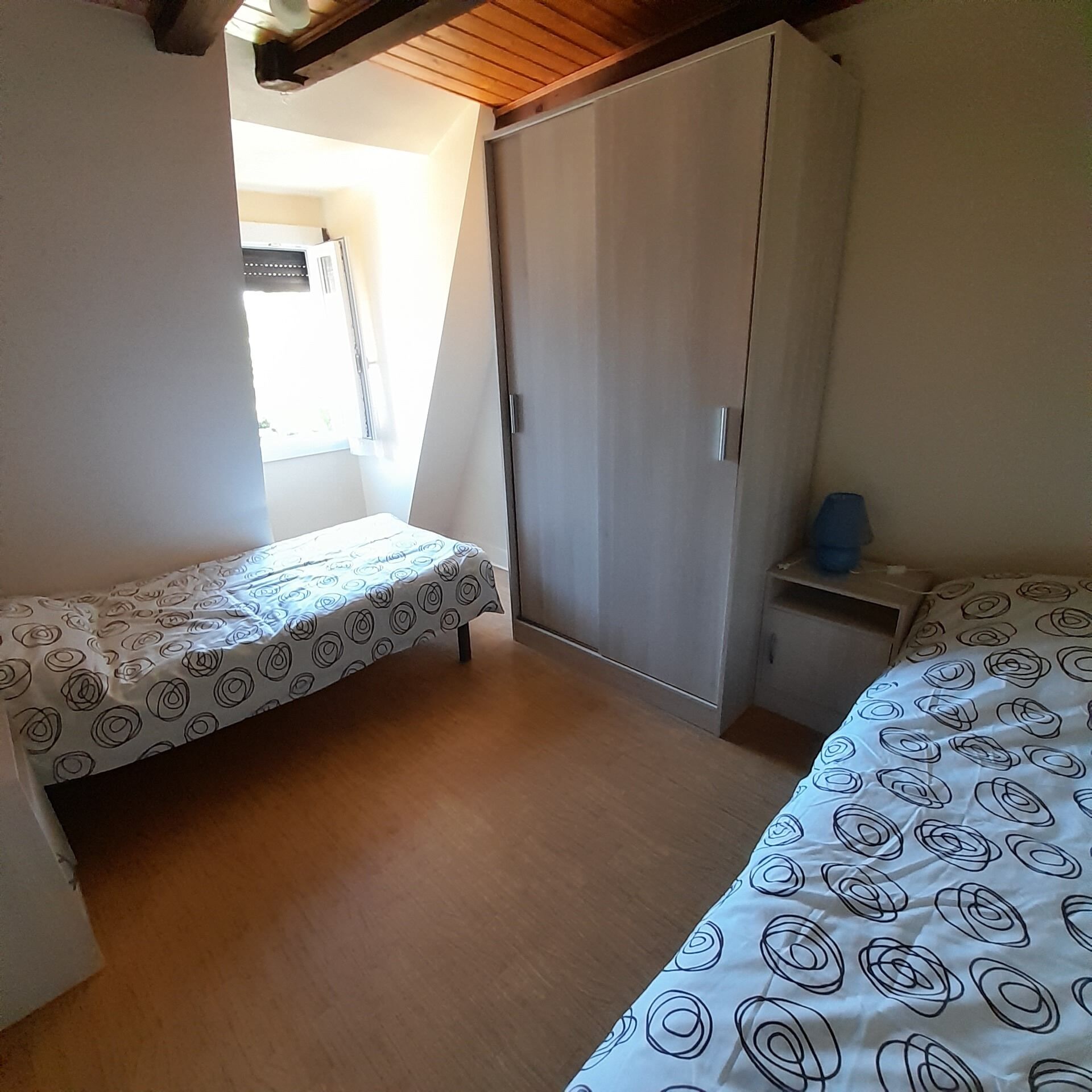 Ein Schlafzimmer mit zwei Einzelbetten, einem Kleiderschrank und einem kleinen Tisch.