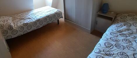 Ein Schlafzimmer mit zwei Einzelbetten, einem Kleiderschrank und einem kleinen Tisch.