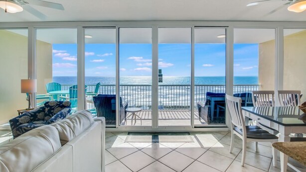A balcony with a view of the ocean, furnished with a sofa, chairs, and a table. - Sanibel 1604 (Gulf Shores)