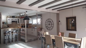 Una cocina moderna con armarios blancos, un comedor con sillas de mimbre y un gran reloj de pared.