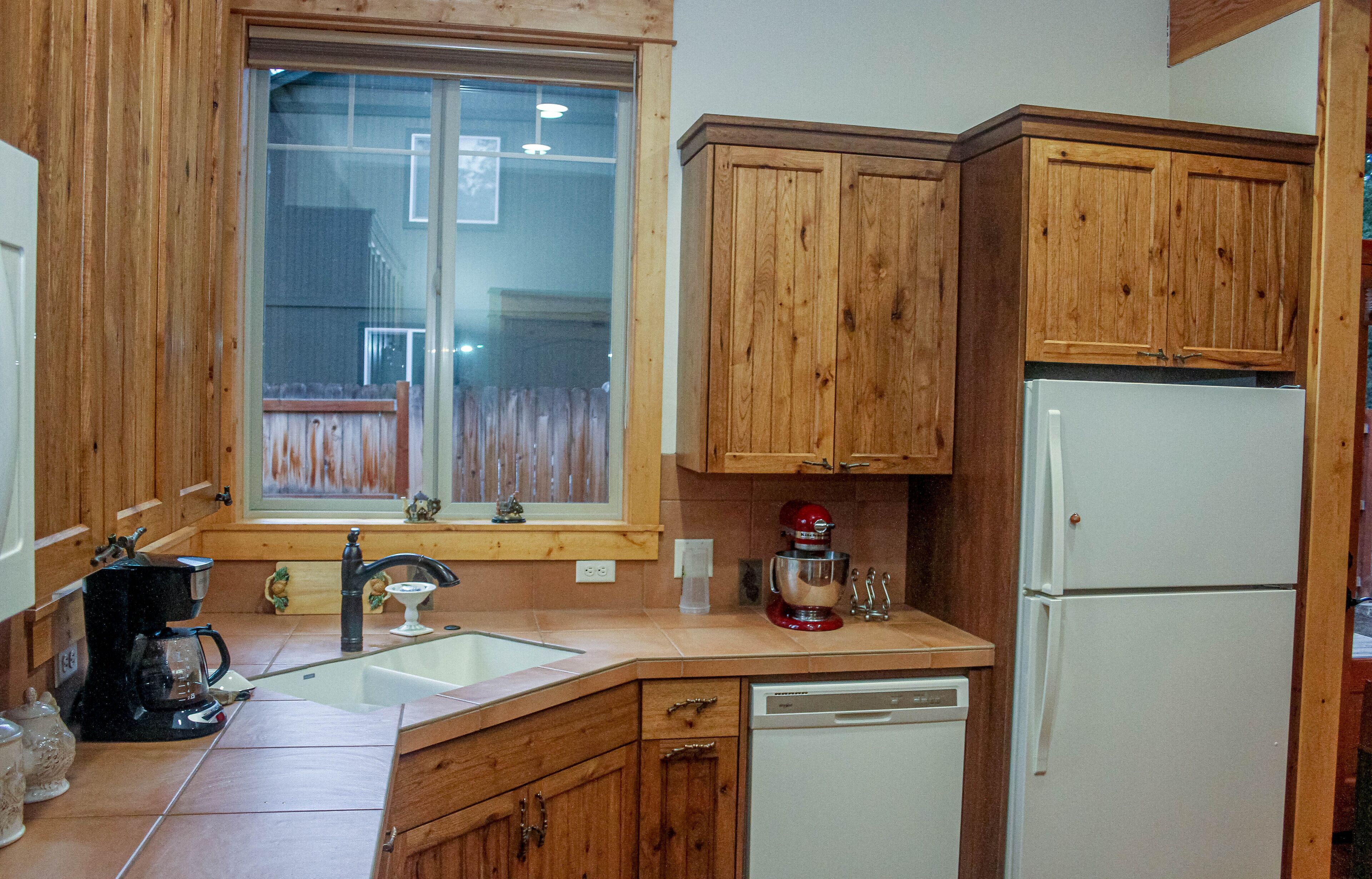 A kitchen with wooden cabinets, a sink, a coffee maker, and a refrigerator.