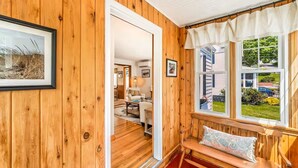 Ein Holzinstrument mit einer Bank, einem gerahmten Bild und Blick auf ein Haus durch ein Fenster.