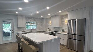 A modern kitchen with a central island, stainless steel appliances, and a view to a patio. - Tropical oasis with amazing tiki (West Palm Beach)