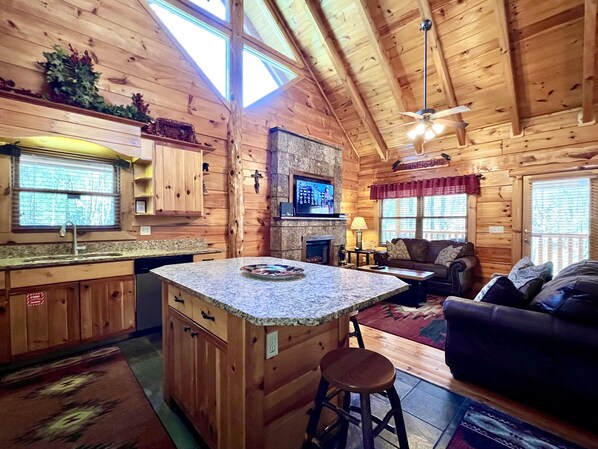 A cozy cabin interior with a kitchen, living area, and a fireplace.