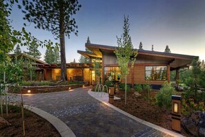 Stunning two-story building with a curved roofline, surrounded by a beautifully landscaped garden and large windows.