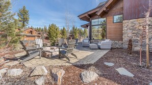 A modern house with a stone exterior, a patio with outdoor furniture, and a view of surrounding trees. - Tahoe Dreamy Destination at Schaffer's Mill Ski Lounge, Golf & Club Amenities (Truckee)