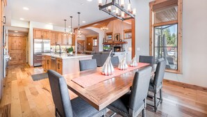 A spacious kitchen with wooden cabinets, a central island, and a dining area with a large wooden table and chairs. - Tahoe Dreamy Destination at Schaffer's Mill Ski Lounge, Golf & Club Amenities (Truckee)