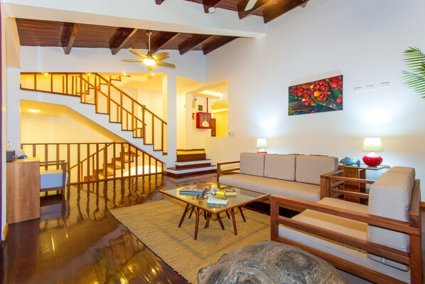A spacious living area with a staircase, a sofa, a coffee table, and a painting on the wall.
