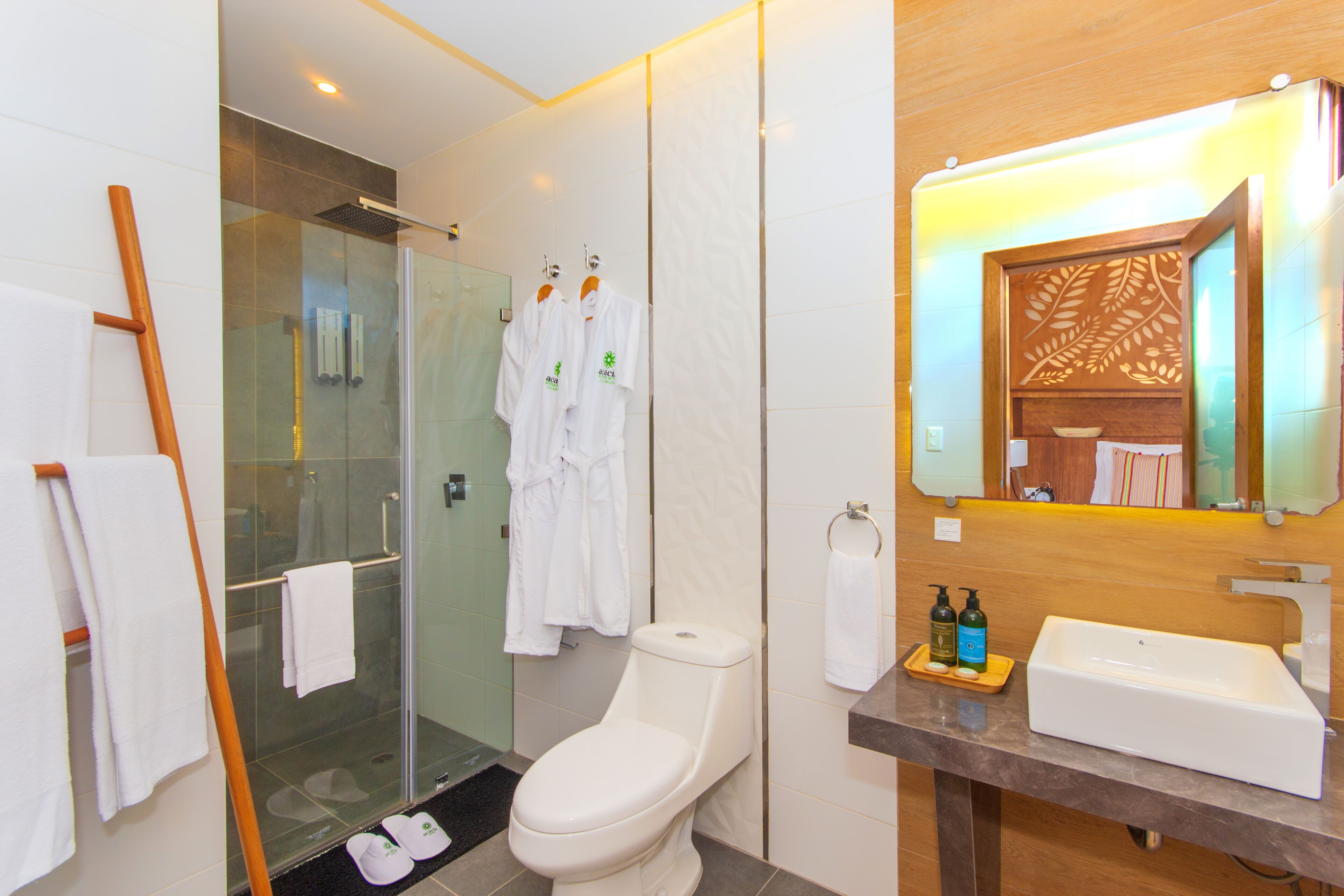 A modern bathroom with a glass shower enclosure, a white toilet, and a vanity with a sink and mirror.