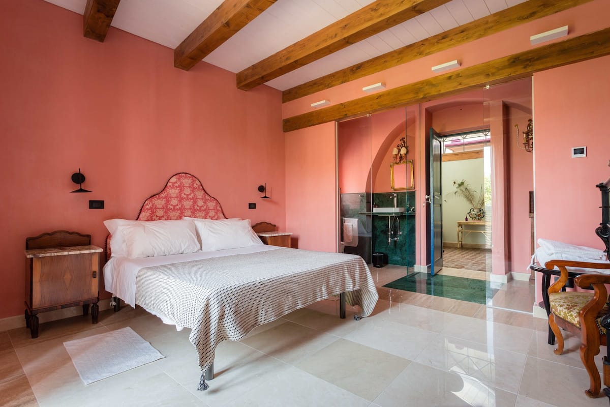 A bedroom with a bed, wooden headboard, nightstands, and a chair.