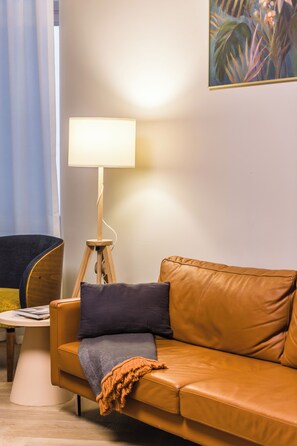 Een moderne woonkamer met een leren bank, een vloerlamp en een klein bijzettafeltje.