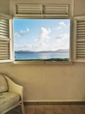 A room with a window overlooking a body of water and distant mountains. - Sea view from Villa Parme (Le Robert)