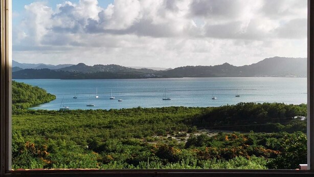 Un paisaje costero con vista al mar, barcos y montañas lejanas.