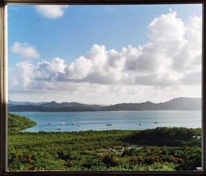 Eine Küstenlandschaft mit Blick auf das Meer, Boote und ferne Berge.