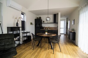 A modern kitchen with a dining area, wooden flooring, and black chairs. - Vacation home with waterfront access (Anjum)