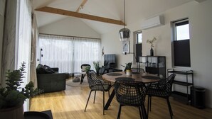 A modern living room with a dining area, featuring a wooden ceiling, large windows, and a variety of furniture including a sofa, chairs, and a table. - Vacation home with access to the water (Anjum)