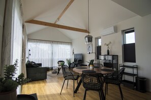 A modern living room with a dining area, featuring a wooden ceiling, large windows, and a variety of furniture including a sofa, chairs, and a table. - Vacation home with access to the water (Anjum)