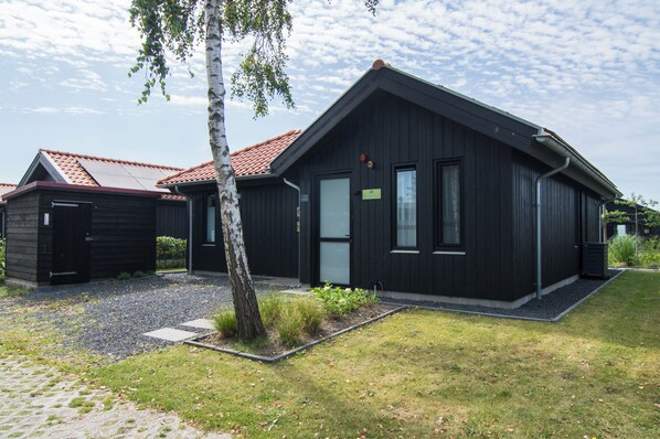 A modern two-story building with a dark exterior, a sloped roof, and a small front garden. - Vacation home with access to the water (Anjum)