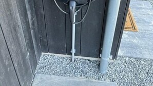 Une borne de recharge pour véhicules électriques, mobile et alimentée à l’électricité, fixée à une clôture en bois.
