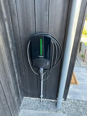 Una estación de carga portátil para vehículos eléctricos montada en una valla de madera.