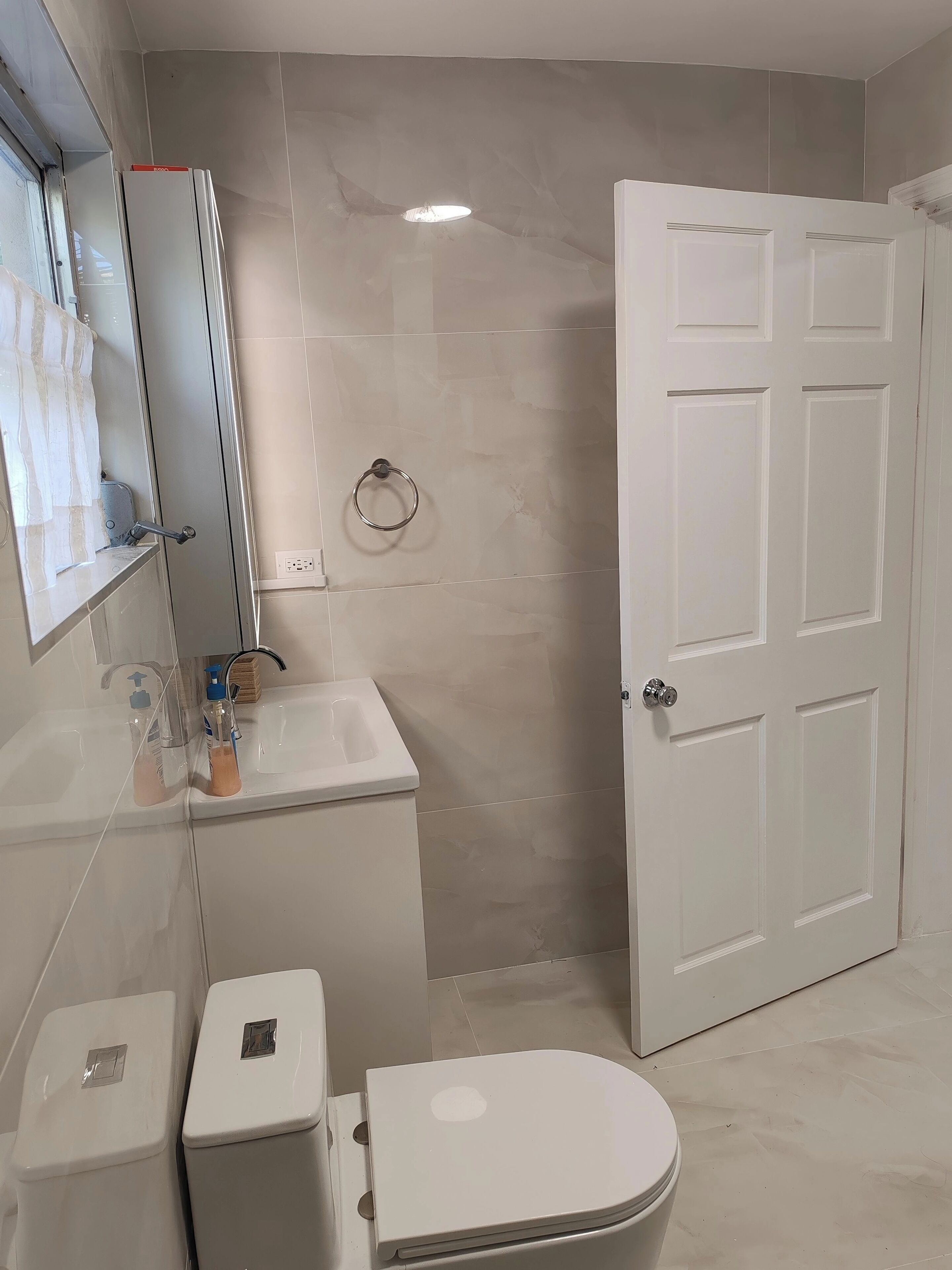 A bathroom with a toilet, sink, and mirror.