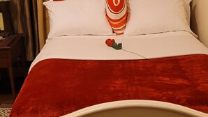 Un lit avec une tête de lit blanche, une literie rouge et blanche, et un oreiller à rayures.