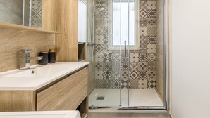 A modern bathroom with a shower, a sink, and a mirror. - Spacious, cosy and chic apartment (Laval)