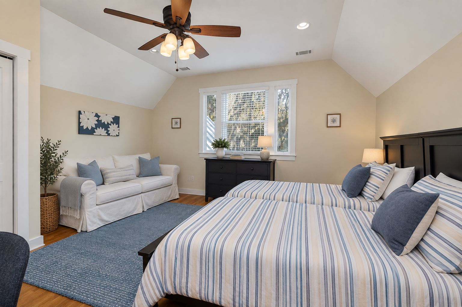 A bedroom with a bed, a sofa, a window, and a ceiling fan.