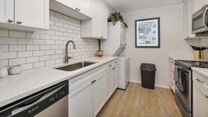 Een moderne keuken met witte kasten, een roestvrijstalen spoelbak en een vaatwasser.