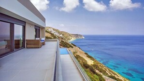 A modern building with a balcony overlooking a coastal view. - Sparkling ocean views with heated pool (Rodhia)