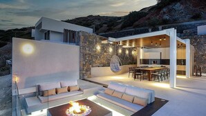 Un espacio exterior moderno con una chimenea, zona de estar y mesa de comedor.