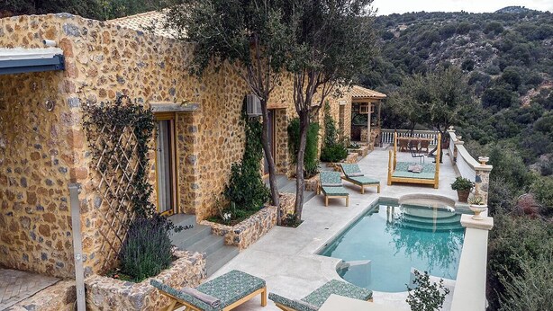 A stone villa with a pool, outdoor seating, and a view of the surrounding hills. - Unique 4 bedroom villa with total privacy (Agios Nikolaos)