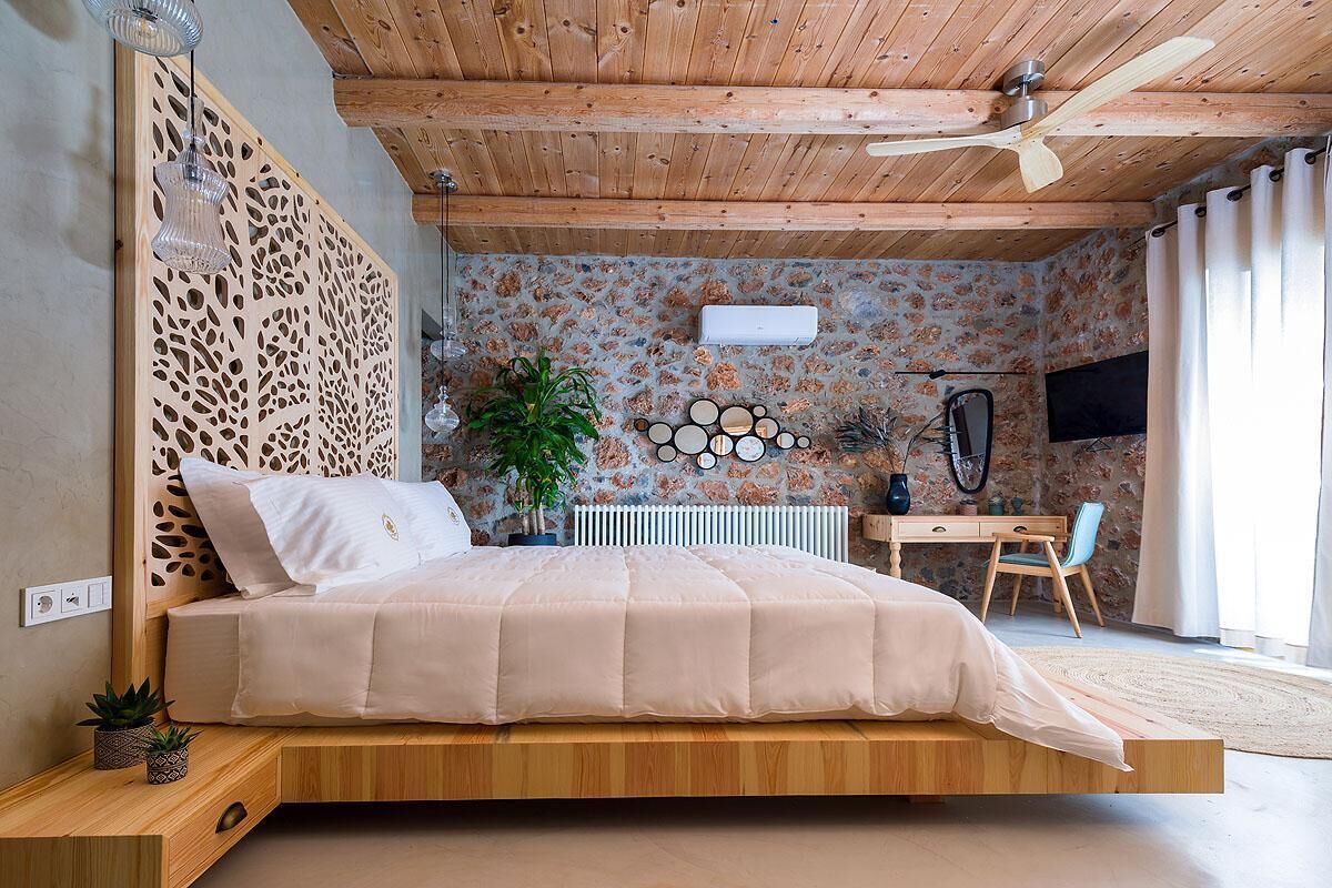 Een moderne slaapkamer met een houten plafond, een bed met een houten frame, een bureau, een stoel en een radiator.