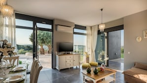 A modern living room with a dining area, a television, and a sofa. - Exclusive 9 bedrooms | heated pool (Perivolia)