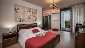 A modern hotel room with a large bed, a bedside table, a nightstand, a bathroom with a glass shower enclosure, and a balcony with a view. - Exclusive 9 bedrooms | heated pool (Perivolia)