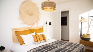 A neatly arranged bedroom with a bed, a bedside lamp, a hanging basket, and a door leading to another room. - 6 bedroom villa in etretat (Étretat)