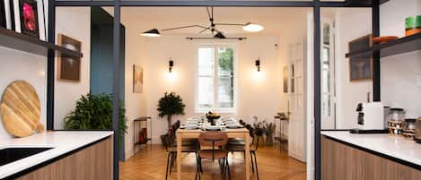 A modern kitchen with wooden flooring, a dining area with a table set for four, and a ceiling fan.