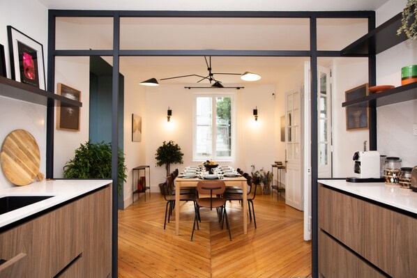 A modern kitchen with wooden flooring, a dining area with a table set for four, and a ceiling fan. - 6-Bedroom Villa in Étretat (Étretat)