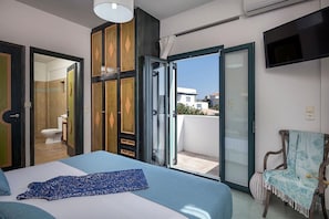 Relax in a spacious room with a large bed, flat-screen TV, and sliding glass door leading to a balcony with a view.