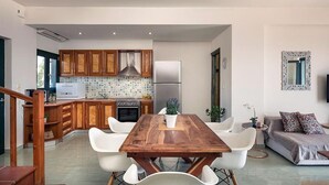 Eine moderne Küche mit Holzausstattung, einem Edelstahlkühlschrank und einem Essbereich mit Holztisch und weißen Stühlen.