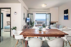 Enjoy meals with a view of the sea from this dining area featuring a large table and comfortable seating.