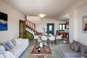 Una sala de estar moderna con un sofá, una mesa de comedor con sillas, una escalera y una cocina al fondo.